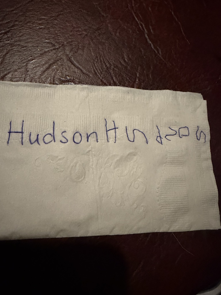 Child's name "Hudson" is written in blue marker on a white napkin.