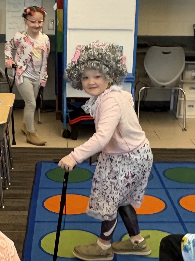 Child dressed as an elderly woman walking with a cane in the classroom.