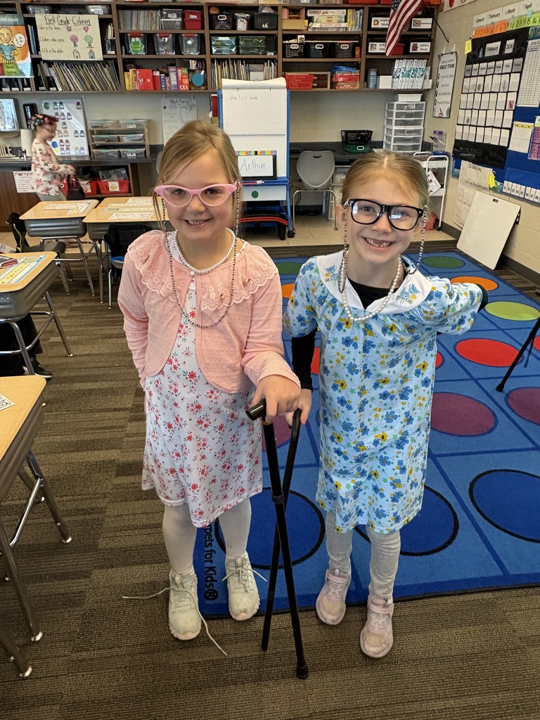 Two girls wearing glasses and floral dresses, pretending to be elderly.