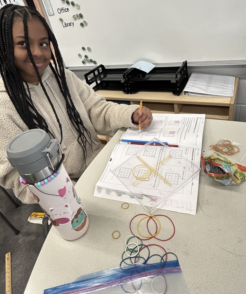 Smiling student works on a math activity with rubber bands and a clear pegboard.