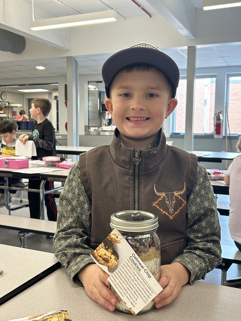 A smiling student holds a completed oatmeal chip cookie jar mix with a recipe tag attached.