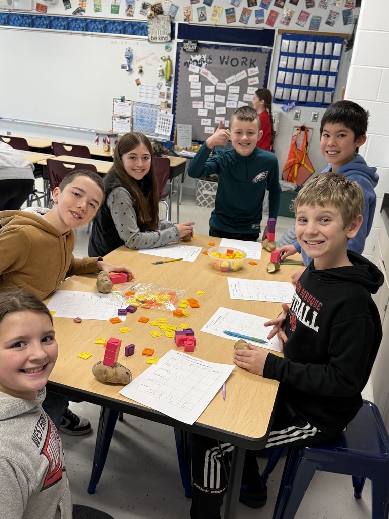 Group of students seated around a table use potatoes and colorful blocks to build and explore a classroom math activity.