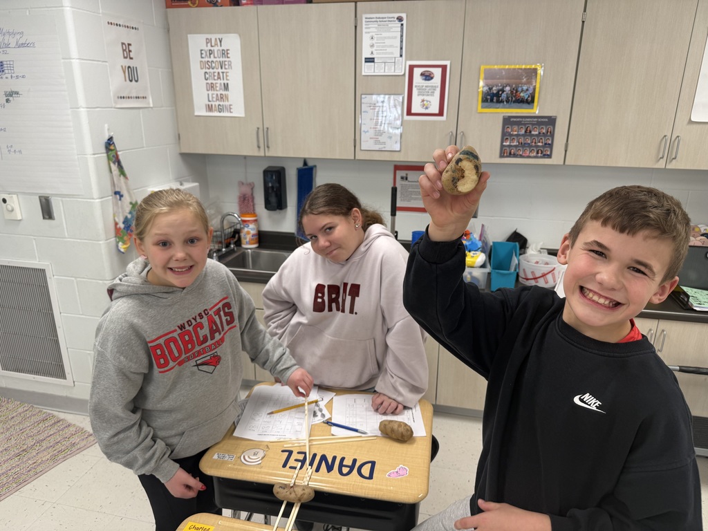 students at a desk hold and examine potatoes while working together on a hands-on classroom activity.