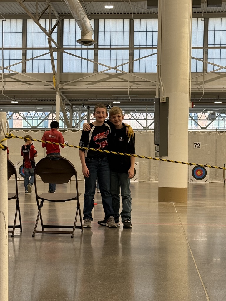 Two boys standing with an arm around each other.