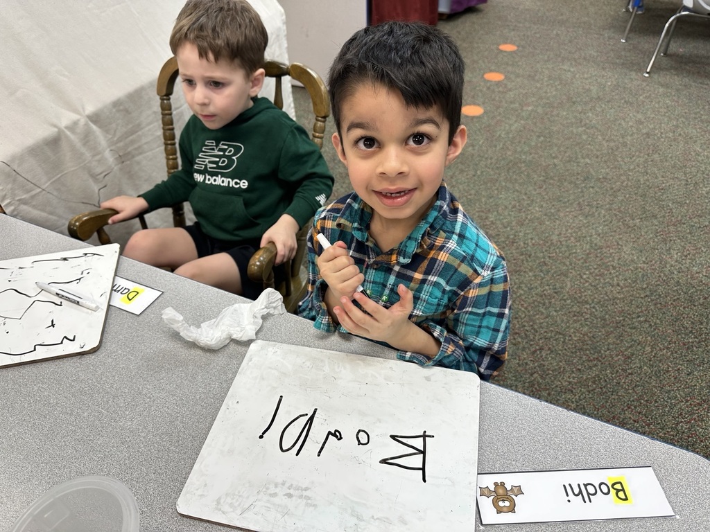 Two boys practicing writing on a markerboard.