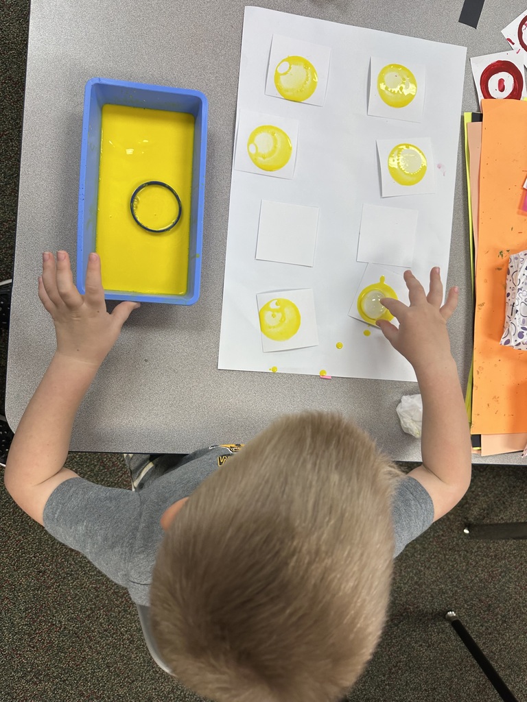 A child painting yellow circles.