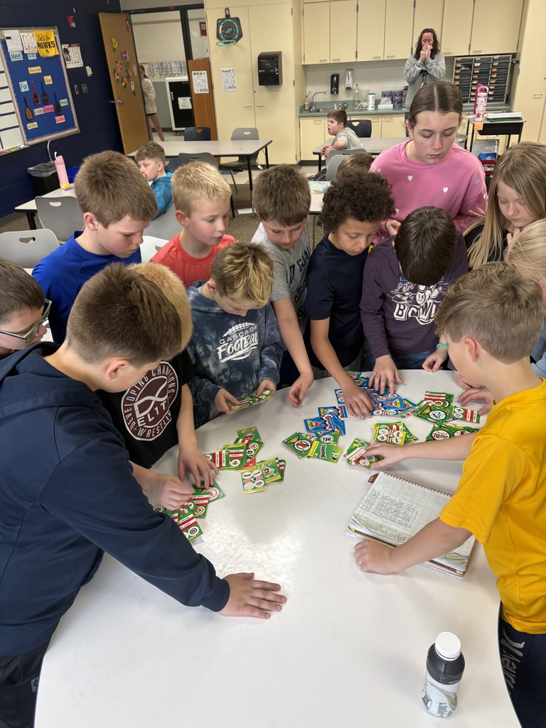 Students standing around a table looking at baseball cards.
