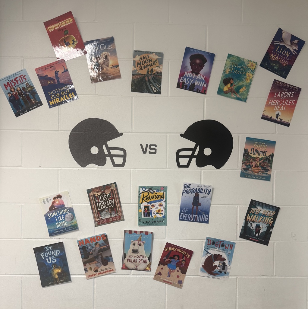 Book covers arranged on a wall around two football helmet icons with “vs” between them, suggesting a reading competition theme.