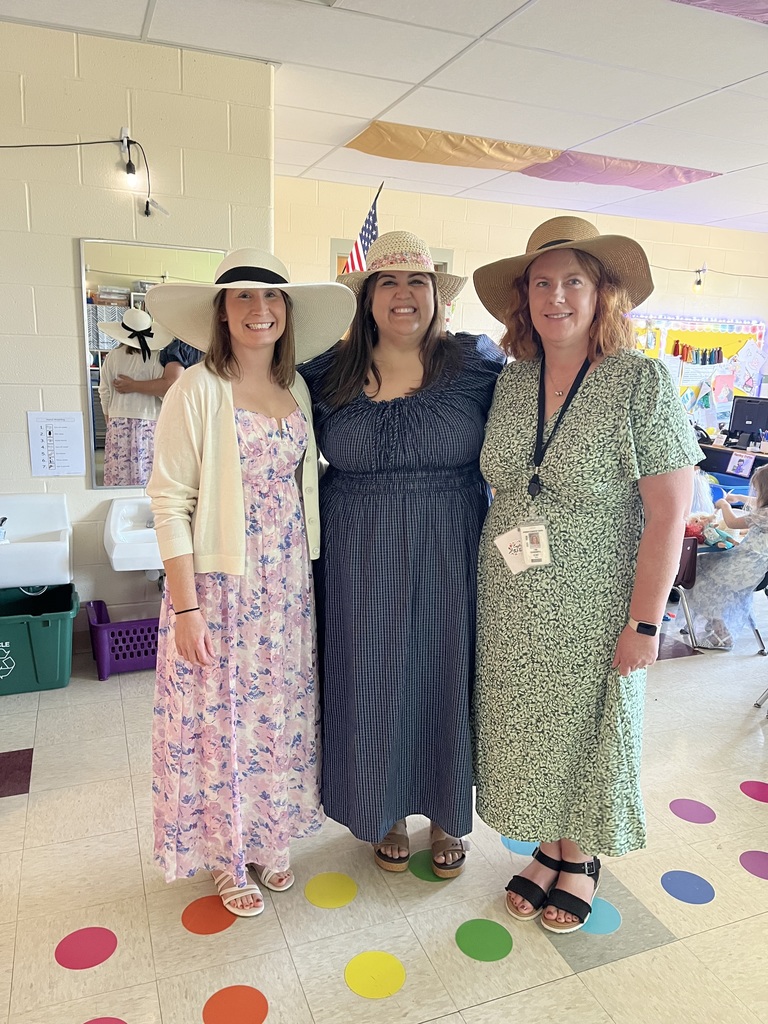 Kindergarten students and teachers dressed in spring hats enjoy a classroom tea party with snacks, tea cups, and colorful decorations.