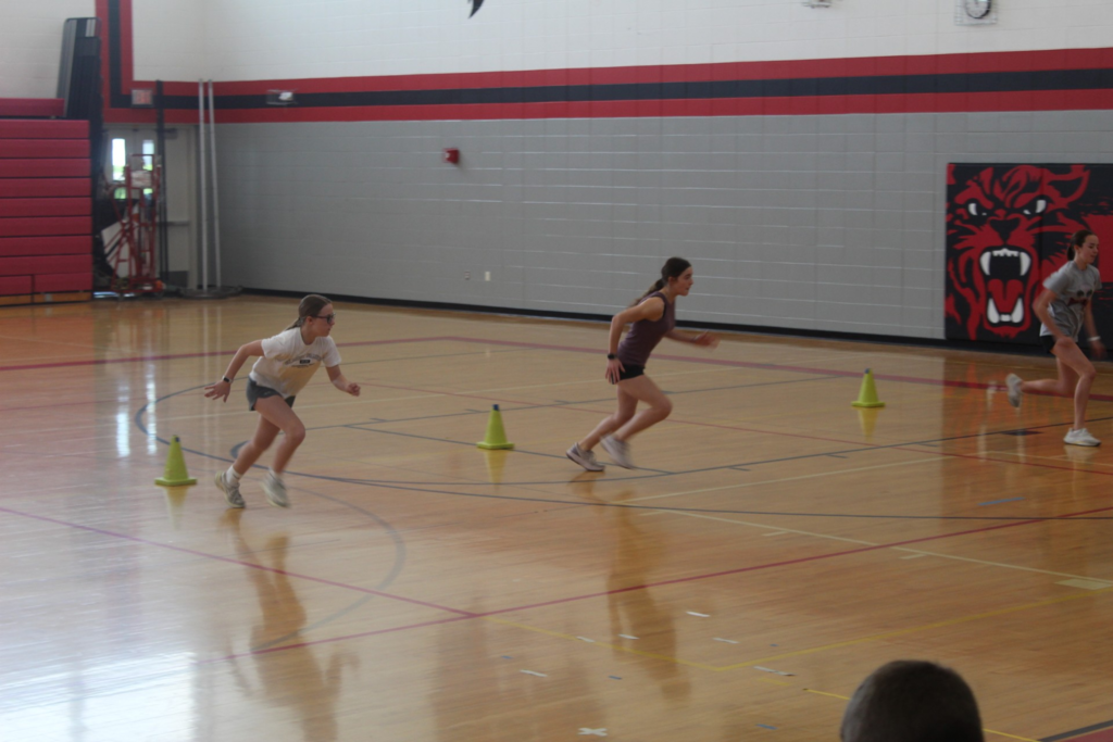 Students race through cone drills during a speed and agility workout in the gymnasium.