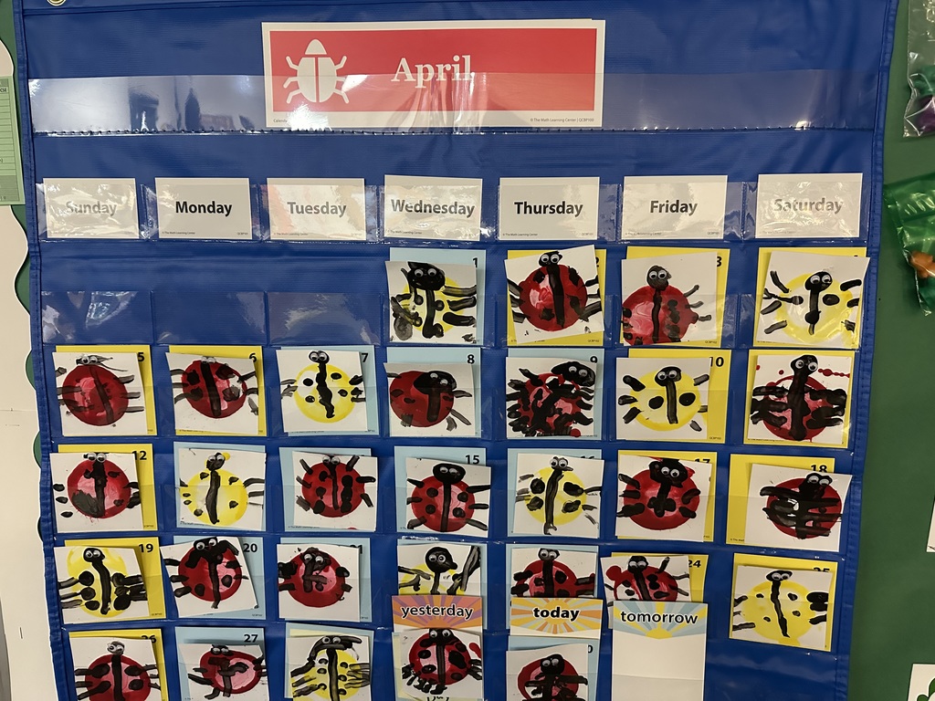 Classroom April calendar displays student-made ladybug artwork for each day of the month.