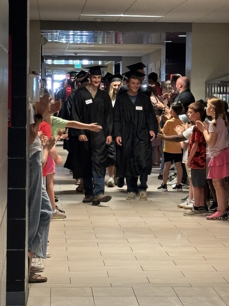 Students with graduation gowns and hats walking through the halls