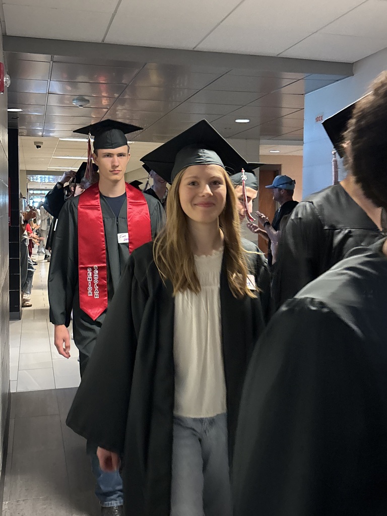 Students with graduation gowns and hats walking through the halls
