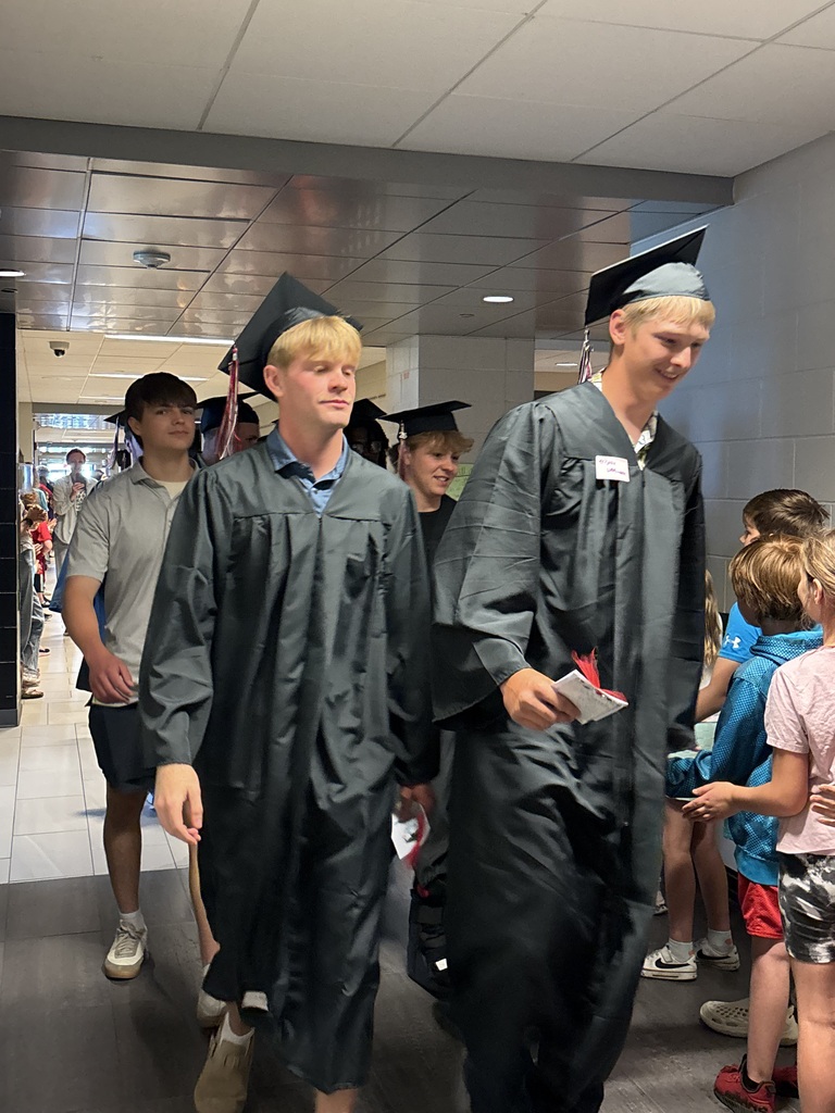 Students with graduation gowns and hats walking through the halls