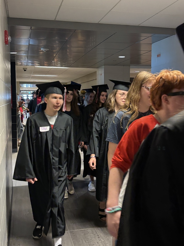 Students with graduation gowns and hats walking through the halls