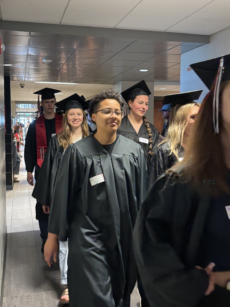 Students with graduation gowns and hats walking through the halls