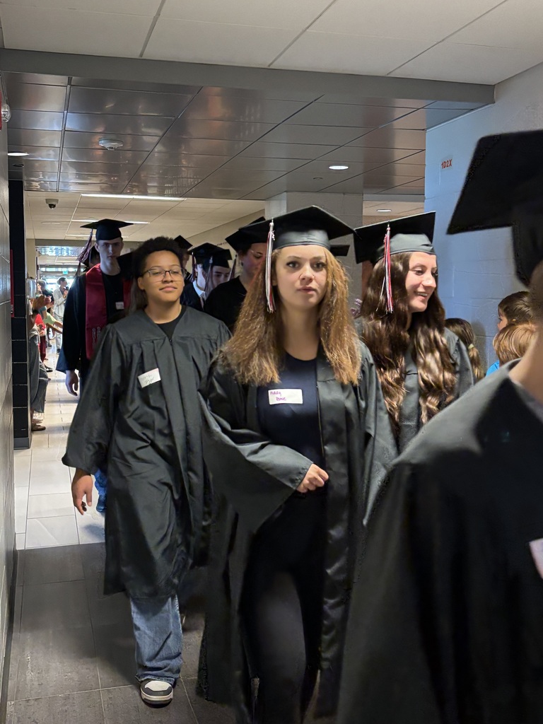 Students with graduation gowns and hats walking through the halls