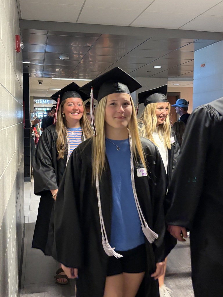 Students with graduation gowns and hats walking through the halls