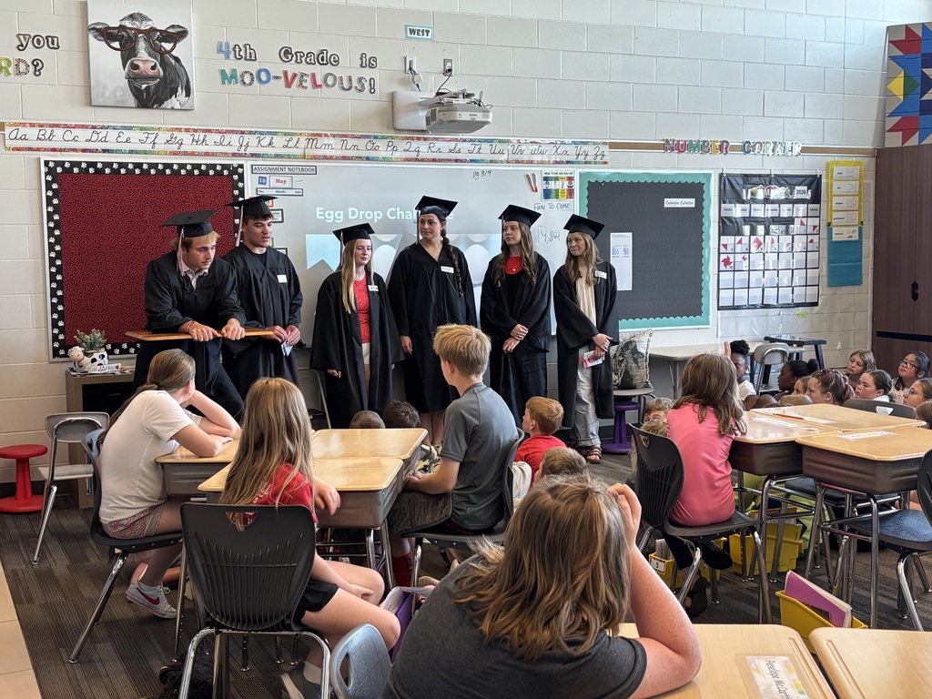 Group of students talking in front of class.