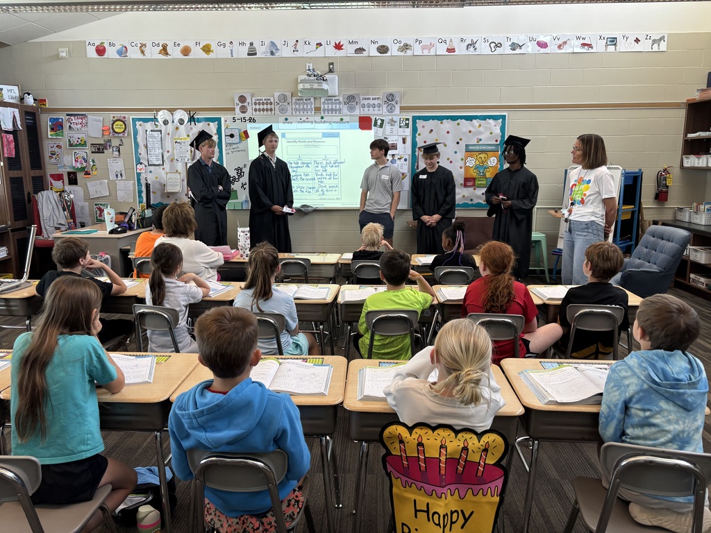 Group of students talking in front of class.