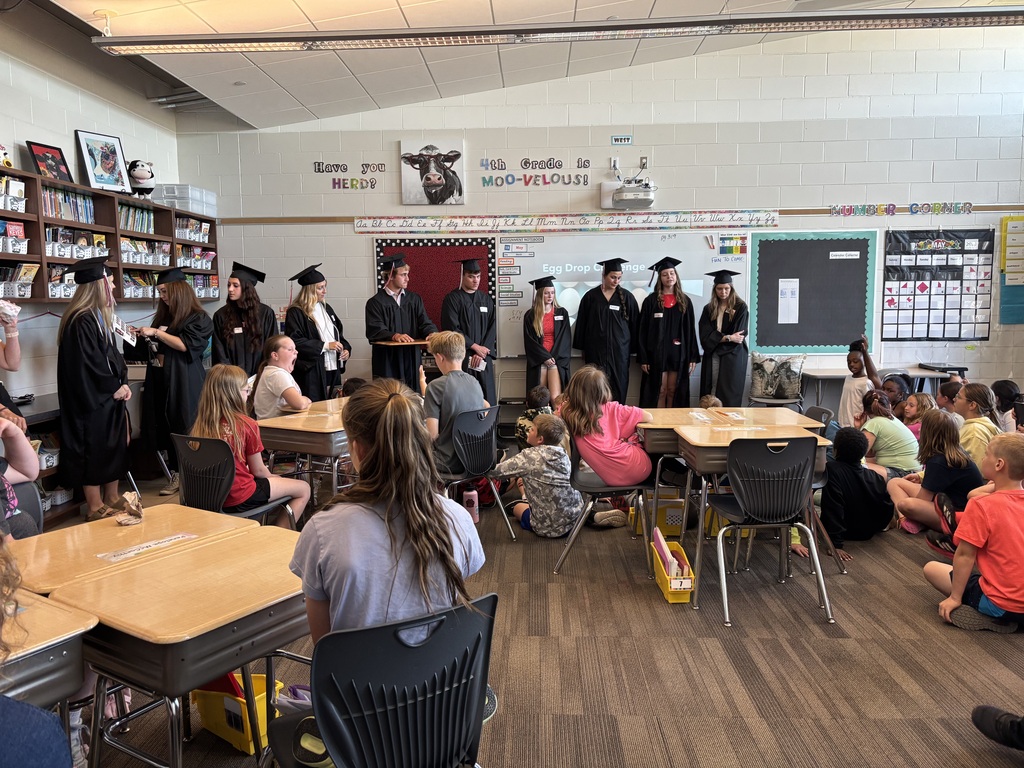 Group of students talking in front of class.