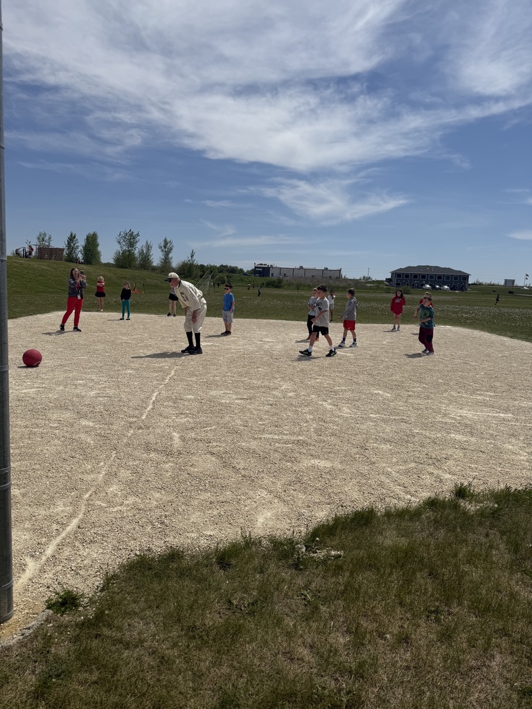 Kids on a baseball field playing with a kickball