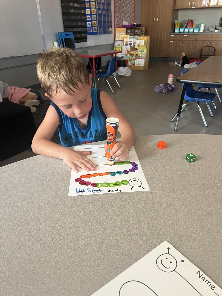 A student uses a colorful marker tool to create a patterned caterpillar during a classroom activity.