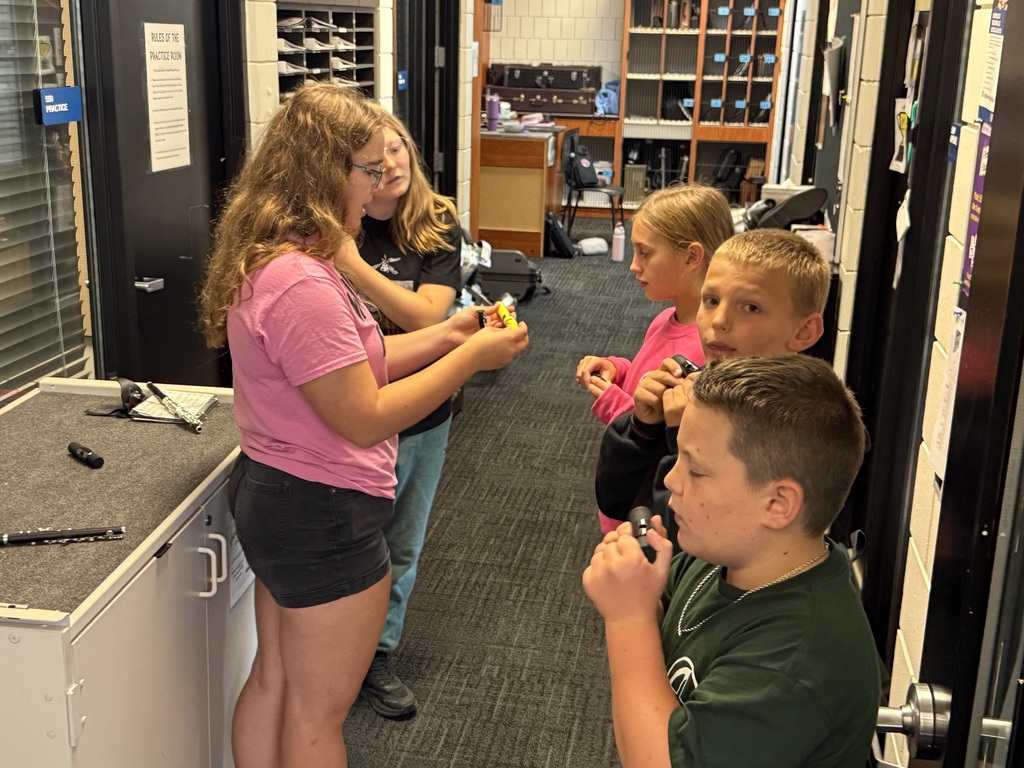 Students standing in a hallway with instruments in their hands.