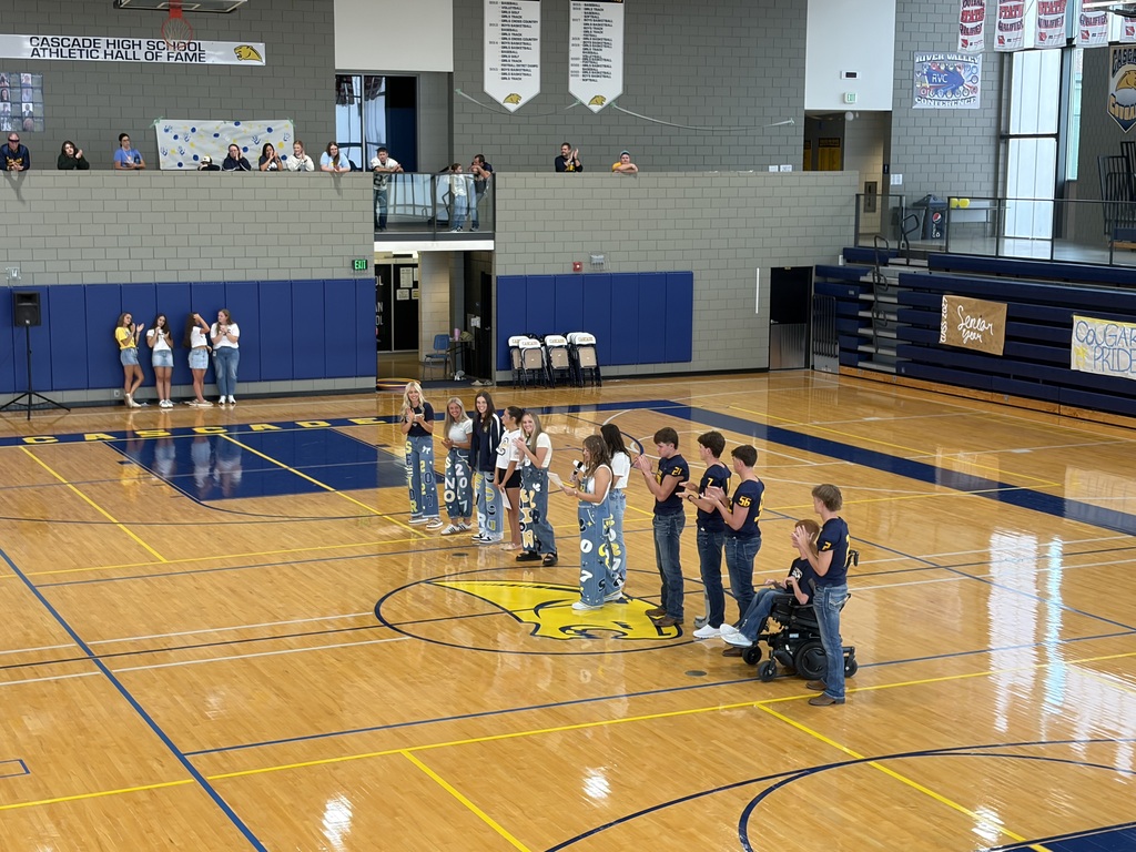 Students line up and applaud at center court during a pep rally, including one student using a power wheelchair.