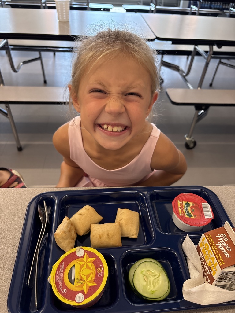 A girl with a school lunch tray in front of her.