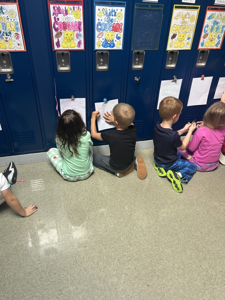 Students drawing on paper that is attached to a locker.