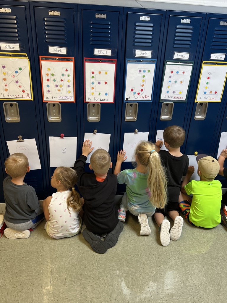 Students drawing on paper that is attached to a locker.