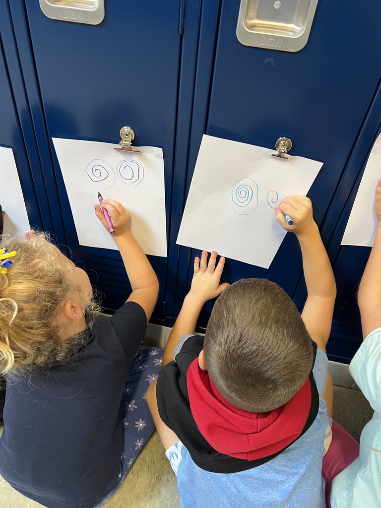 Students drawing on paper that is attached to a locker.