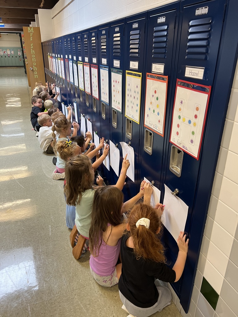 Students drawing on paper that is attached to a locker.