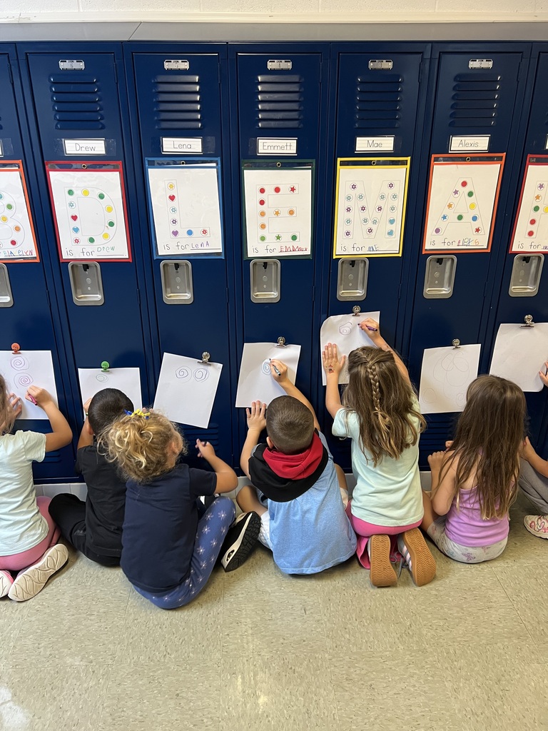 Students drawing on paper that is attached to a locker.