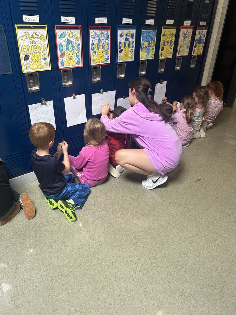 Students drawing on paper that is attached to a locker.