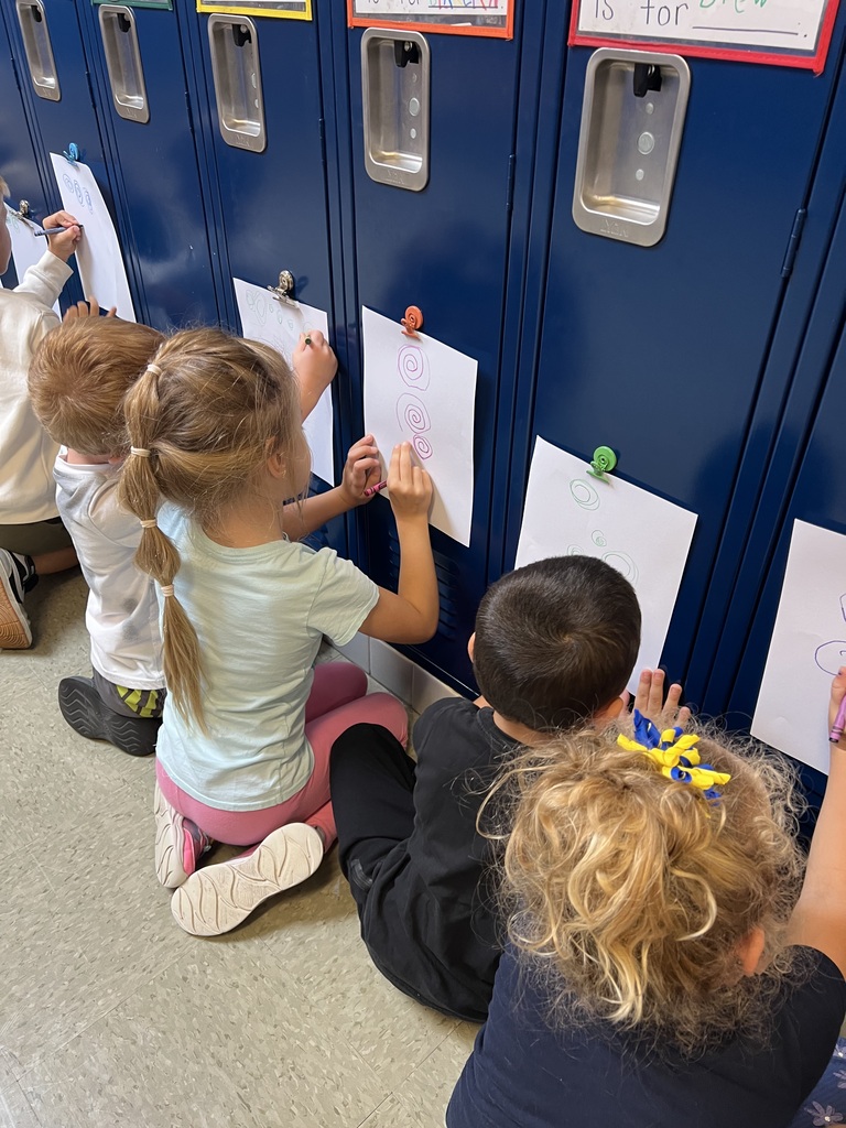 Students drawing on paper that is attached to a locker.