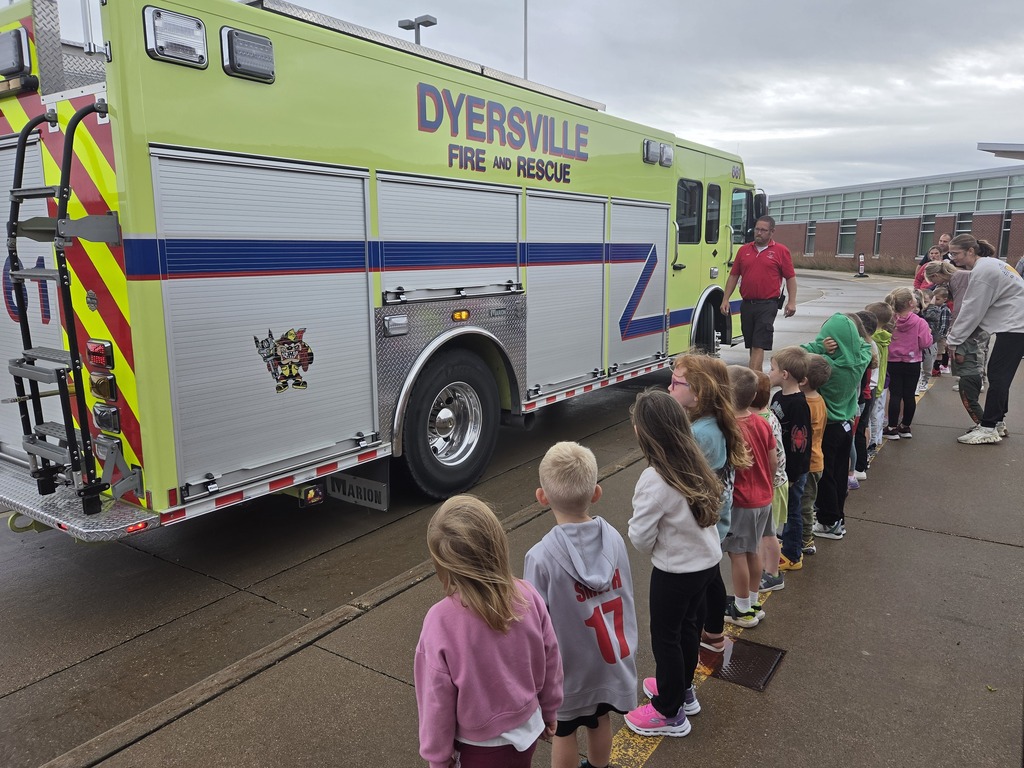 Young students line up beside a large Dyersville Fire and Rescue truck during an outdoor fire safety presentation.