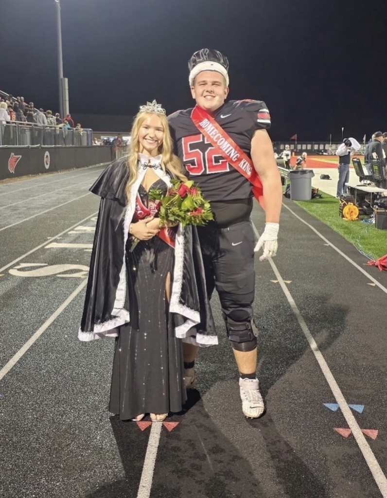 Girl in black dress and boy in football uniform wearing sashes and crowns.