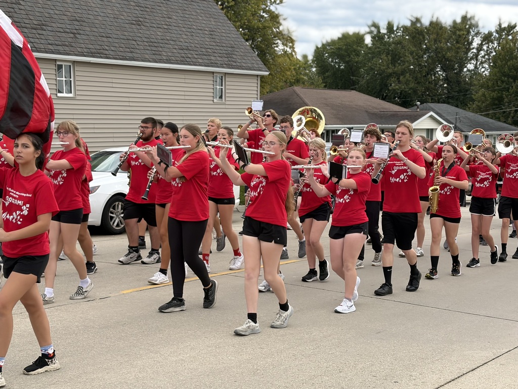 Students wearing red shirts and playing instruments while walking