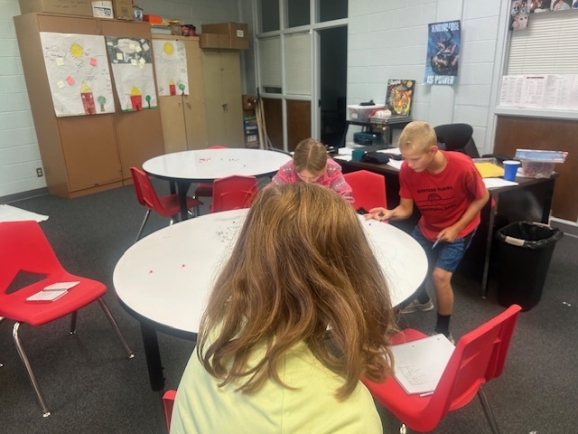 Students playing marbles using pom poms.