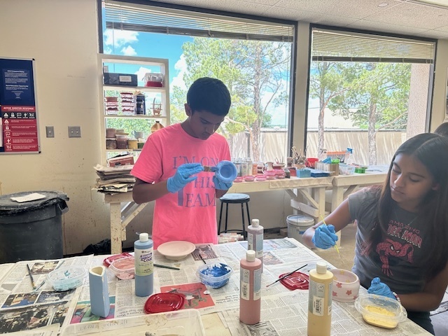 Students paint their pottery pieces.