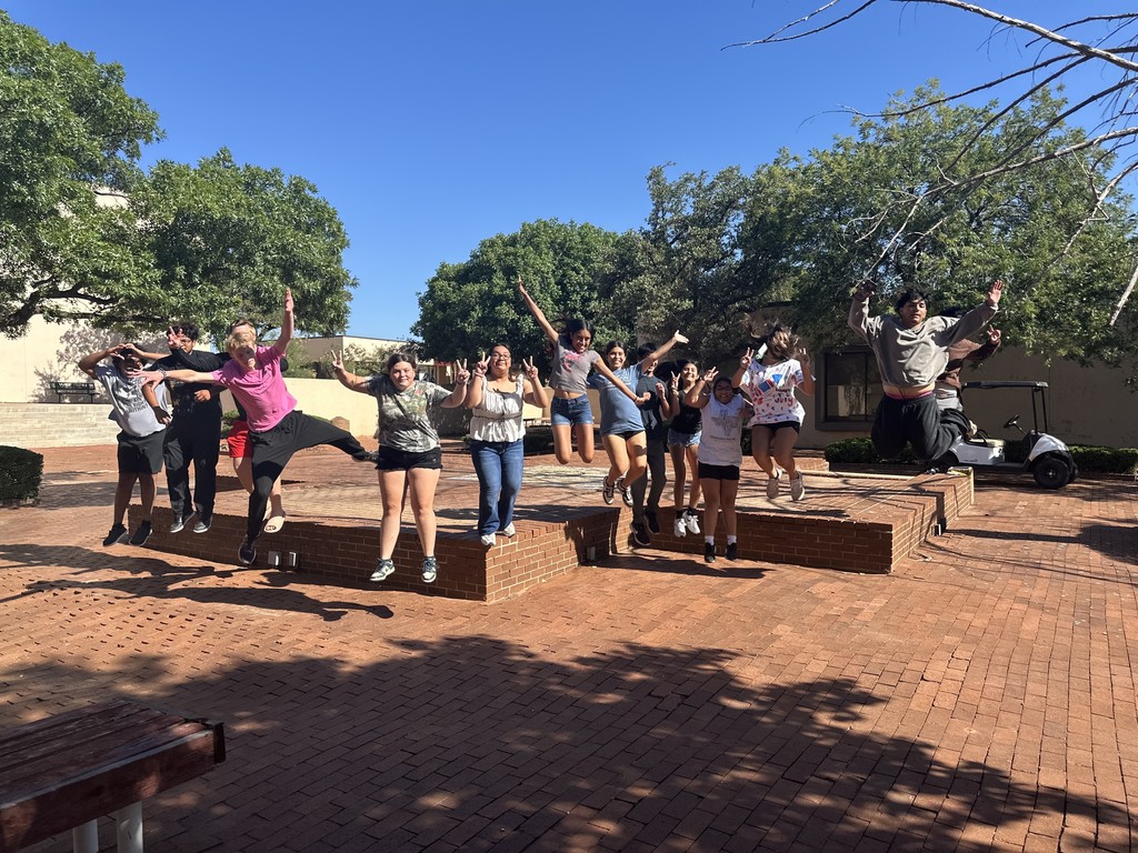 Smiling  students jump off the center island in the courtyard.