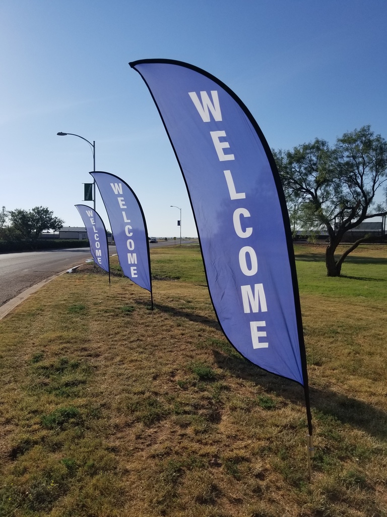 Blue, vertical welcome flags with white text wave gently in the breeze.