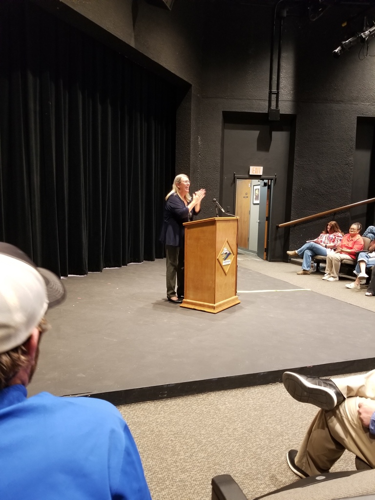 Dr. Beebe laughs while addressing employees from the stage.