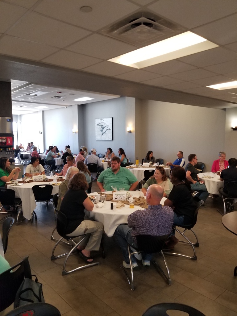 Employees sit at covered tables in the Cafeteria enjoying conversation and brunch.