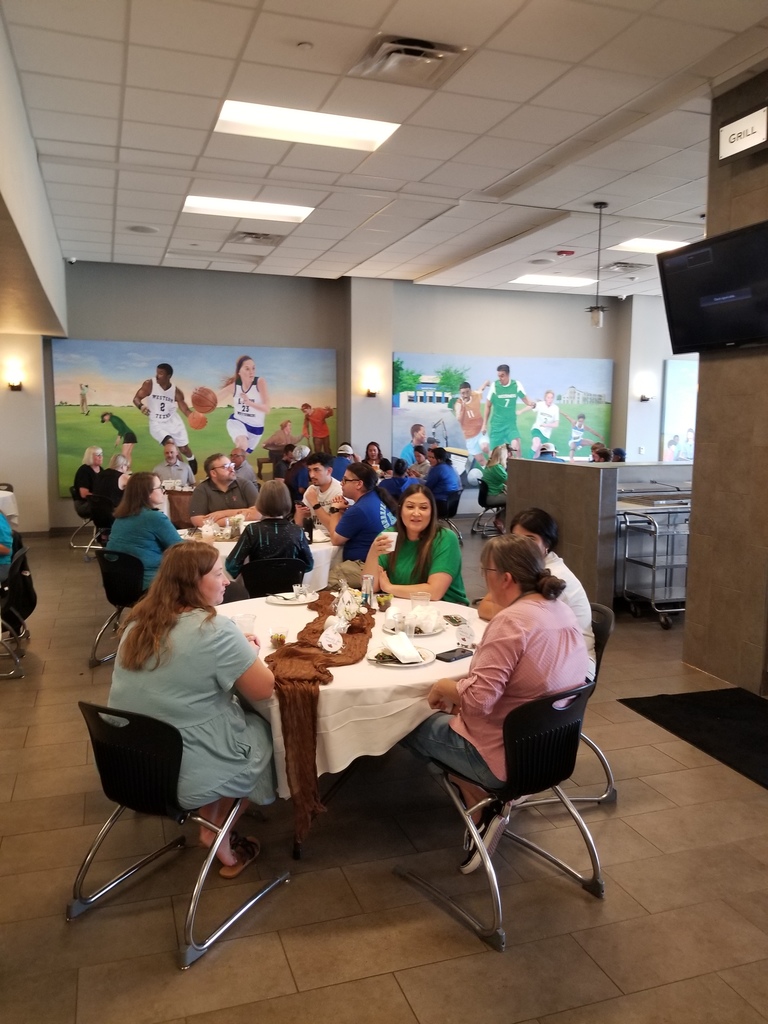Employees sit at covered tables in the Cafeteria enjoying conversation and brunch.