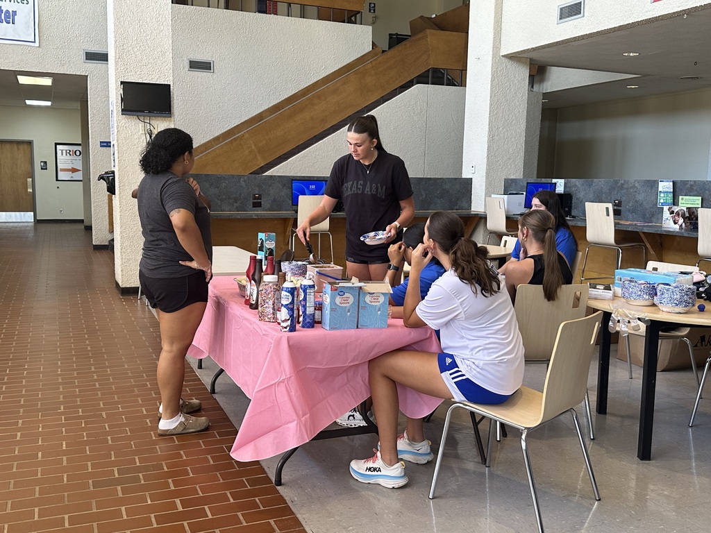 A women's basketball player makes a sundae for a student.