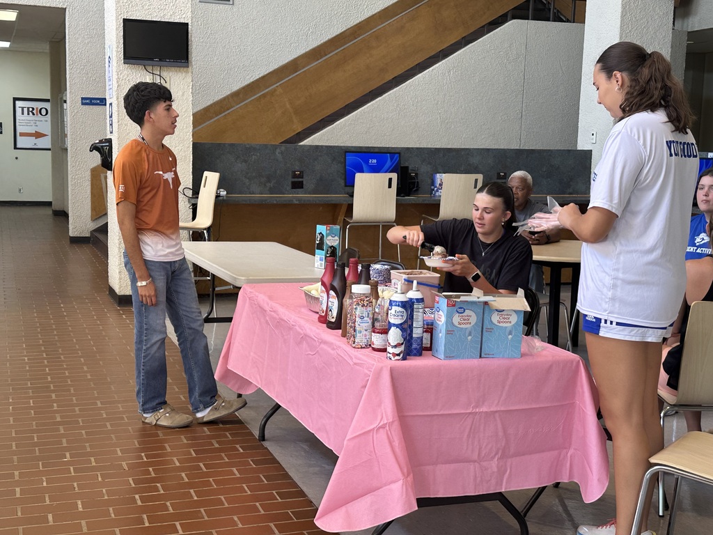A women's basketball player makes a sundae for a student.