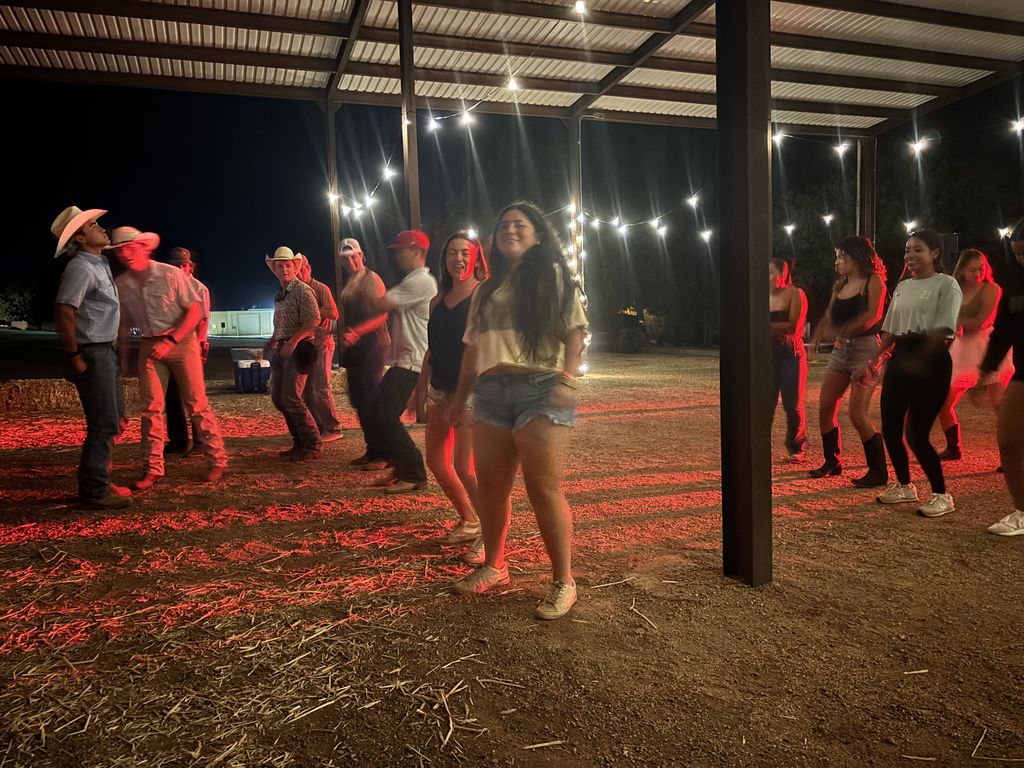 Students laugh and smile while line dance under twinkling lights.